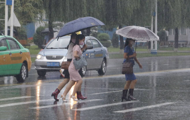 지난 5일 북한의 수도 평양에서 주민들이 세차게 내리는 비를 피해 길을 건너가고 있다. 평양lAFP연합뉴스